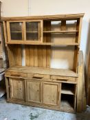 A pine dresser with sliding glazed doors to top, plate rack and sliding doors to base (H202cm W167cm