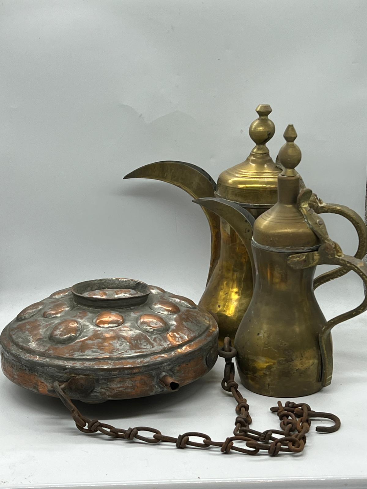 Two Middles Eastern coffee pots and a copper flask/container on a chain