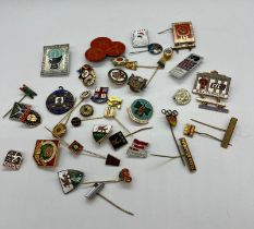 A collection of pin badges and medals mostly of a sporting theme