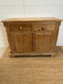 A pine two drawer and two door cupboard with carved doors and supports AF (H76cm W100cm D43cm)