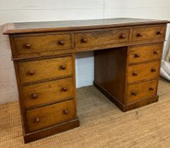 An oak pedestal desk with long central drawer flanked by four shorter drawers to left and right (