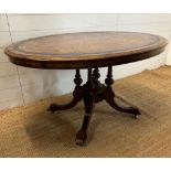 An oval walnut centre table with ebonised inlay and pierced floral detail, on four splayed legs with