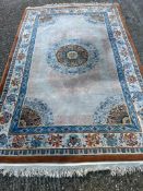 A beige ground wool rug with geometric border and blue and red central medallion 280cm x 180cm