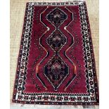 A red ground wool rug with cream and blue geometric boarder 166cm x 110cm