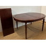 An extendable oval mahogany dining table with brass string inlay on turned legs with an accompanying