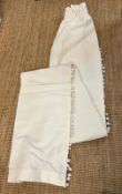 A pair of white curtains with tassel details to side