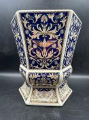 A six sided blue, white and gold planter with a floral bird pattern