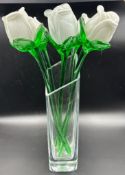 A set of five white and green glass roses in a vase