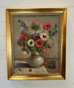 An oil on canvas still life of flowers in a white vase signed lower right 39cm x 48cm