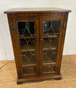 An oak glazed media cabinet with leaded glass and carved detail to doors (H94cm W62cm D49cm)