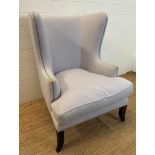 A contemporary wing back arm chair, upholstered in lilac