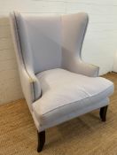 A contemporary wing back arm chair, upholstered in lilac