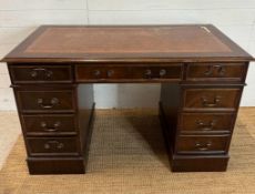 A pedestal desk with brown leather top, a central long drawer flanked on either side by four short