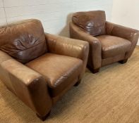 A pair of brown leather club arm chairs