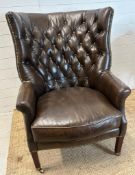 A brown leather button backed wing arm chair by Henredon leather company with brass studs and