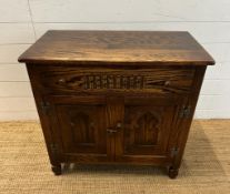An oak two door cabinet with single drawer over and carved panels (H72cm W76cm D44cm)