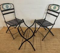 Two black wrought iron garden chairs with tiled mosaic backs and a bistro table frame