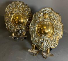 A pair of brass wall sconce, cast backplate with winged cherubs and twin arm candle holders