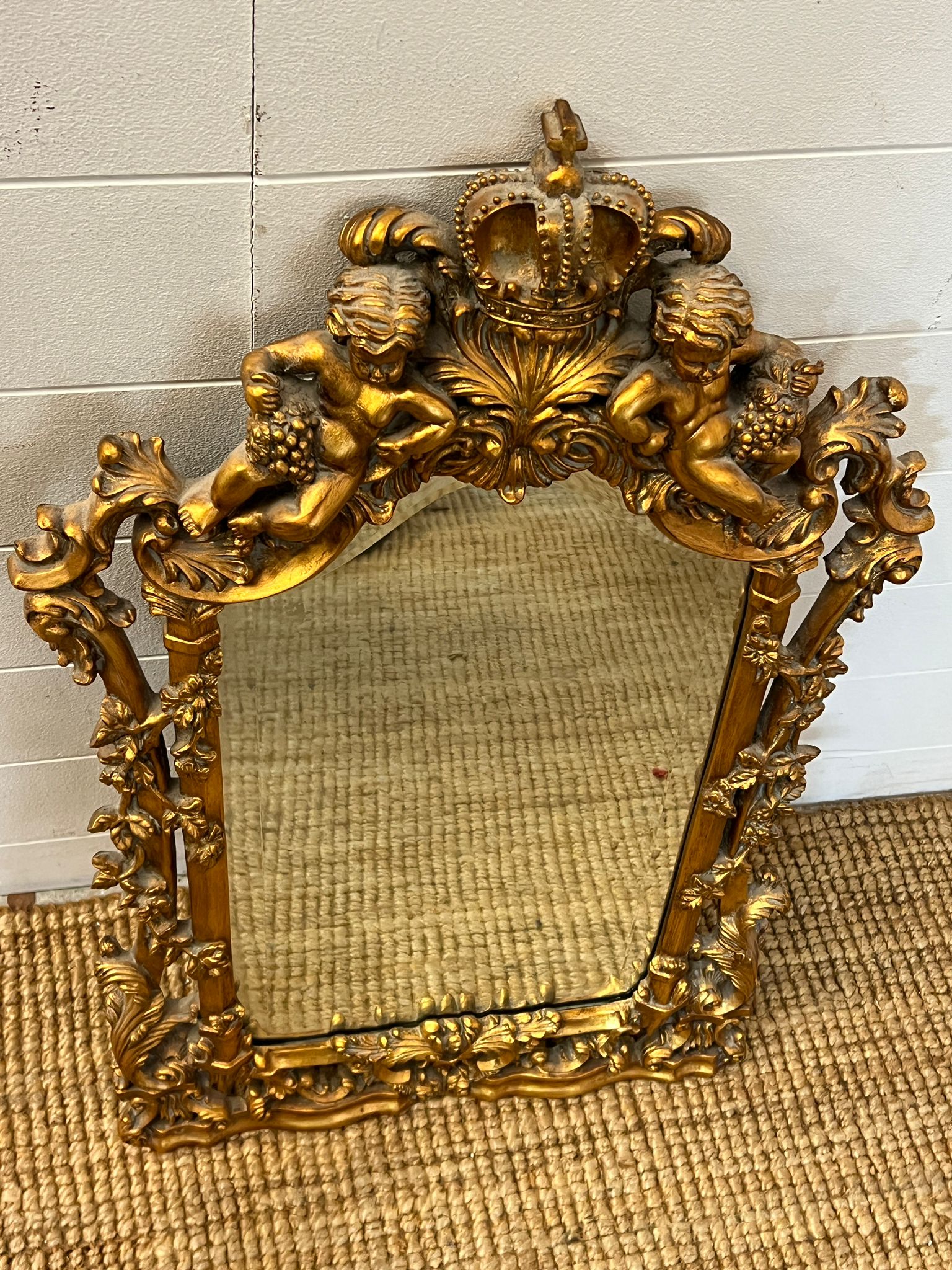 A gilt framed mirror with heavy carved cherubs 78cm x 48cm