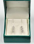 A pair of 18ct white gold set three diamond drop earrings