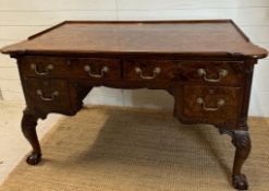a Georgian style walnut knee hole desk with brass drop handles and galleried top on claw and ball