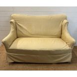 A two seater cream upholstered skirted sofa