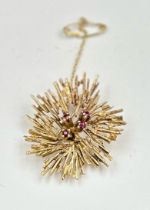 A 9ct gold brooch with floral theme and four small rubies. Approximate total weight 8.6g