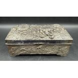 A hammered white metal cigarette box with floral motif, inscribed "Moodys Club" to the front and