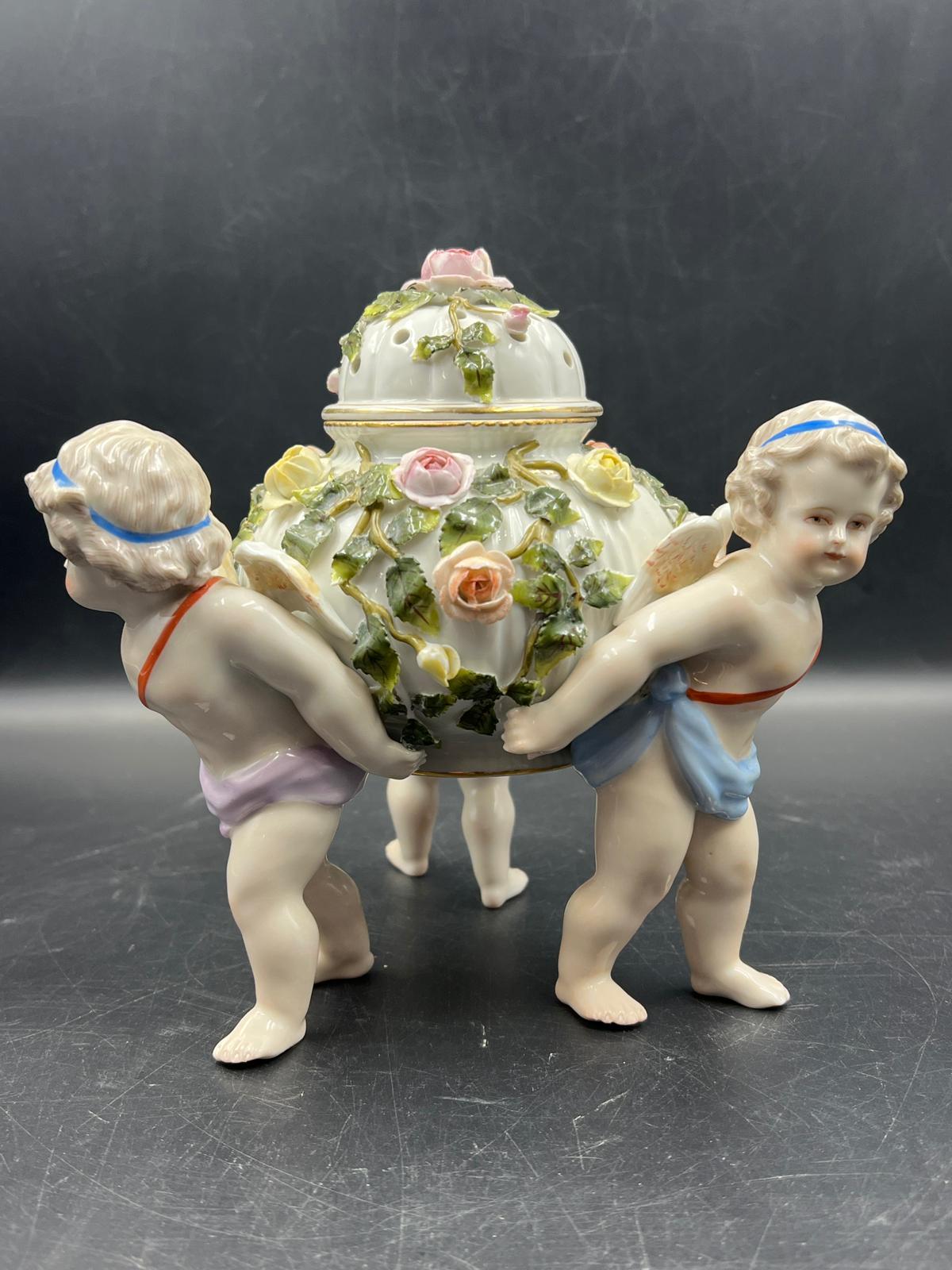 A Sitzendorf porcelain center piece with three cherubs supporting a lidded bowl decorated with