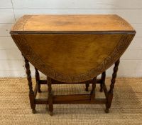 An oak gate leg table with carved top and barley twist legs (H72cm W108cm D74cm extension W37cm