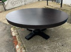 A contemporary black circular dining table on turned centre base (H75cm Dia189cm)