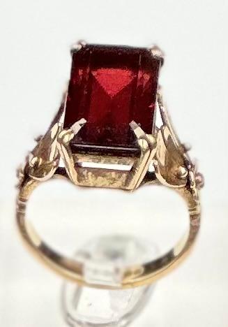 A 9ct gold fashion ring with central red stone, size M and approximate weight 7g