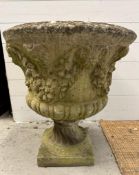 A weathered concrete garden urn with a grape vine design on a square base (H65cm Dia60m)