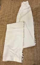 A pair of white curtains with tassel details to side