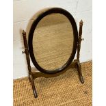 An oval framed bathroom mirror on splayed feet