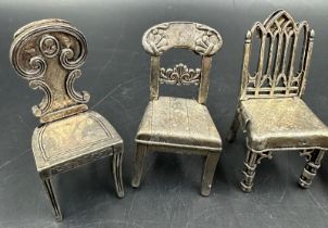 A selection of eight white metal miniature chairs, various styles.