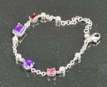 An 18ct white gold bracelet with topaz, amethyst and ruby interspersed by six small diamonds,