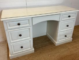 A white painted knee hole dressing table with a glass top, long central drawer flanked by three