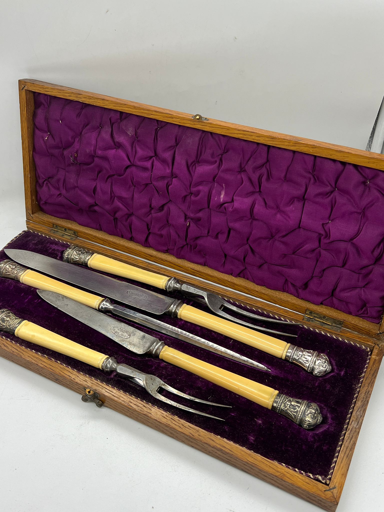A cased carving set with white metal tips decorated with stags and game birds