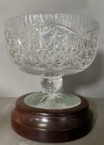 A lead crystal cut stemmed punch bowl on a mahogany plinth