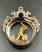 A silver and glass fob featuring a cricketer in action