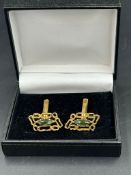 A pair of 18ct gold cuff links with central green stones, hallmarked for London, bearing the