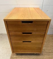 A contemporary three drawer side cabinet on castors