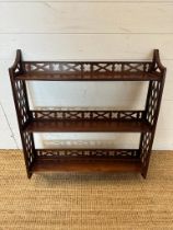 A mahogany three shelf wall hanging bookcase with piece sides and back rail.