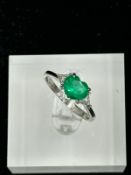 A heart shaped emerald ring with diamond shoulders on an 18ct, marked 750, white gold mount,
