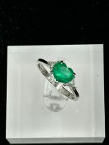 A heart shaped emerald ring with diamond shoulders on an 18ct, marked 750, white gold mount,