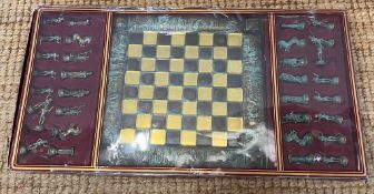 A boxed chess set with bronze effect pieces and metal board