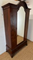 A Victorian mahogany wardrobe with arched hood, the panelled inlaid sides with centre mirrored doors