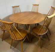 A blondie Ercol circular drop leaf table with six stick back chairs (H72cm W124cm)