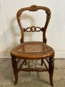 A child's cane seated spoon back chair carved and with turned stretchers